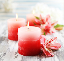 Beautiful candles with flowers on wooden background