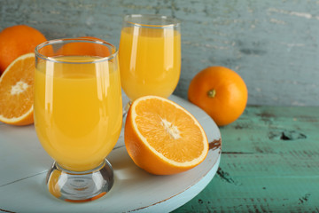 Glass of orange juice with slices on color wooden background