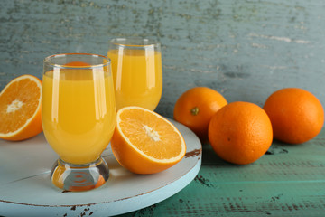 Glass of orange juice with slices on color wooden background