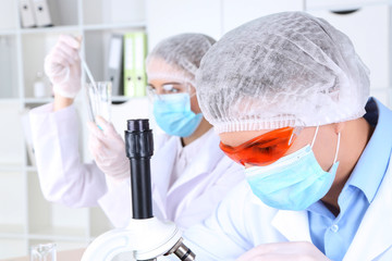 Male and female scientists using microscope in laboratory