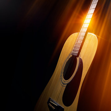 acoustic guitar on a black background in the rays of light