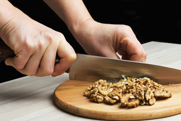 Chopped walnuts with a knife on a wooden cutting board