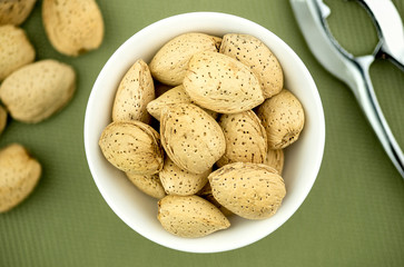 Un-shelled almonds in bowl with nutcracker