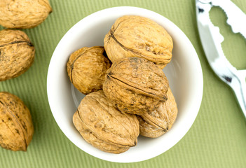 Walnuts in bowl with nut cracker nearby