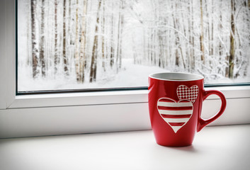 cup with hearts on the background of a winter landscape