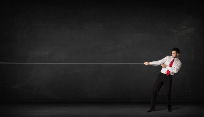 Obraz premium Businessman pulling rope on grey background