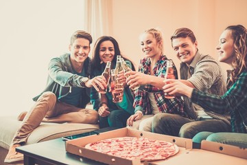 Multi-ethnic friends with pizza and bottles of drinks