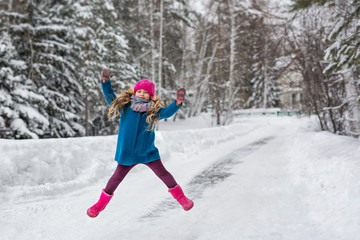 Fototapeta na wymiar Little girl high jumps winter forest