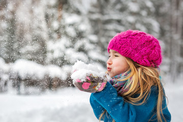 Cute little girl blows snow from hands - 76191185