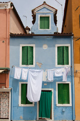 sky blue little house in Burano with white sheets and clothes ha