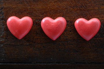 Three red heart on wooden background