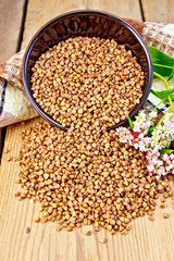 Buckwheat in brown bowl with flower and towel on board