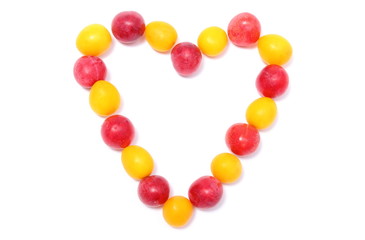 Heart of red and yellow mirabelle on white background