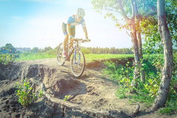 Fototapeta na wymiar Athlete on a mountain bike rides along the dirt road