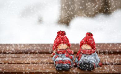 two dolls sitting on desk at winter day, snowing