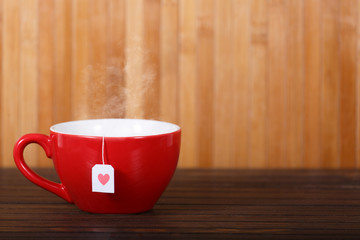 Cup of tea with heart shape on wooden table