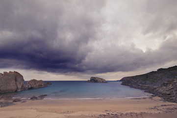 Fototapeta na wymiar Rocky beach in a stormy day with dark cloudy sky
