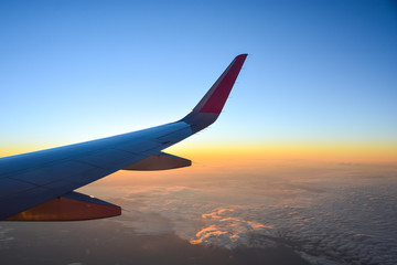Fototapeta premium airplane flying over clouds with evening sky