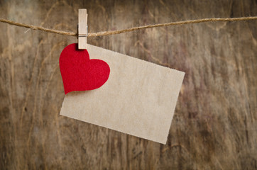 Red fabric heart with sheet of paper hanging on the clothesline