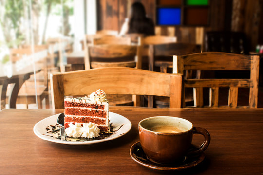Coffee cup with slice of cake on wood table in cafe
