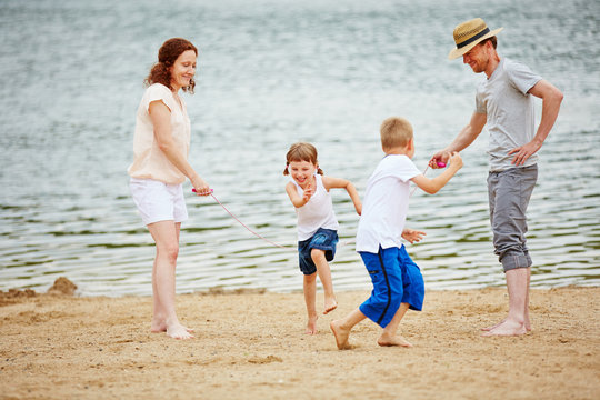 Familie mit Kindern beim Seilspringen am Strand