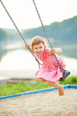 Lachendes Mädchen schaukelt im Sommer