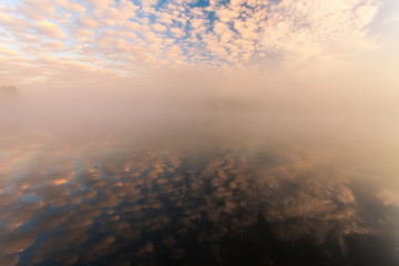misty morning on the river and clouds reflected in water