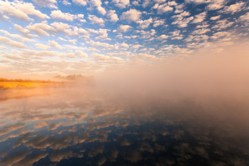 misty morning on the river and clouds reflected in water