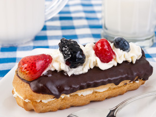 Chocolate eclair with berries and whipped cream on top