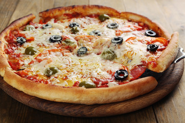 Pizza with cheese on board and wooden table background