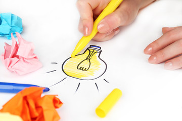 Female hand drawing symbol of idea as light bulb