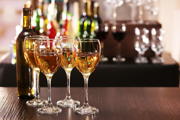 Glasses of wine on counter and bar on background
