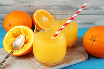 Glass of orange juice with straws, spoon and slices