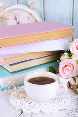Cup of tea with books and flowers on wooden background