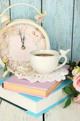 Cup of tea with books and flowers on wooden background