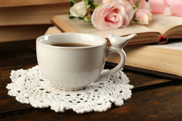 Cup of tea with books and flowers on wooden background