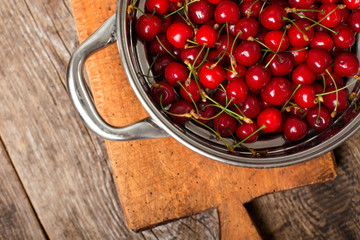 Sweet cherries in colander on color wooden background