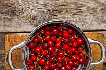 Sweet cherries in colander on color wooden background