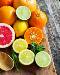 Naklejka na ściany i meble Halves of fresh citrus fruits on wooden background. Orange, grap
