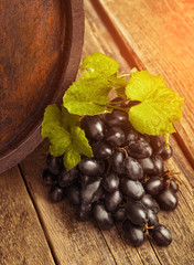 Grapes with leaves and barrel on the wood background close up