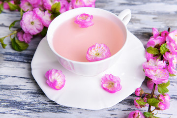 Beautiful fruit blossom with cup of tea on table close-up