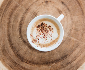 Cappuccino coffee cup on the annual wood table   