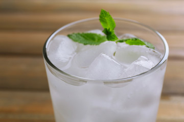 Glass with ice cubes on wooden table
