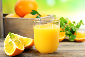 Glass of orange juice with crate of oranges and slices