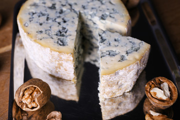 Blue cheese with nuts on metal tray and wooden table background
