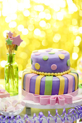 Delicious birthday cake on shiny yellow background