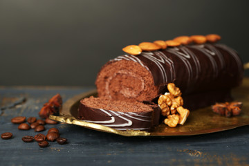 Delicious roll cake on wooden table, on dark background
