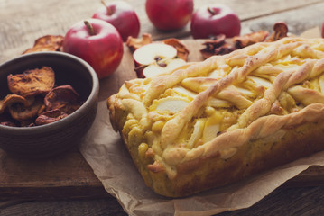 Apple pie on a board with fresh apples