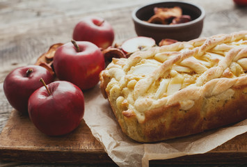 Apple pie on a board with fresh apples