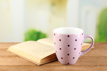 Cup of tea and book on table, on bright background